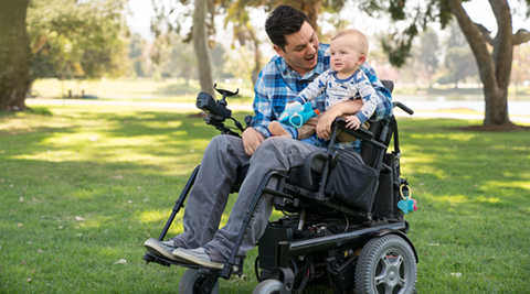 Man in a wheelchair holding a baby